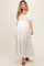 woman wearing a white maternity dress with floral embroidery and puff sleeves, showcasing her baby bump