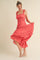 woman wearing a coral ruffled midi dress with a fitted bodice and flared skirt, striking a playful pose