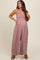 woman wearing a floral print maternity jumpsuit with a smocked bodice and ruffle strap details, showcasing her baby bump