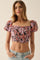 woman wearing a black floral crop top with puffed sleeves and a square neckline