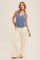 woman wearing a denim blue peplum tank top and cream wide-leg pants