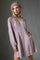 woman wearing a lavender long sleeve dress with smocked details and buttons, styled with a beige beret