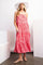 woman wearing a pink tropical print maxi dress with a tiered design and a wide-brimmed hat