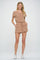 woman wearing a tan short sleeve romper with drawstring waist and white sneakers