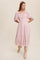 Woman wearing a light pink midi dress with puff sleeves and tiered skirt paired with beige knee-high boots