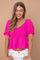 woman wearing a hot pink smocked peplum top with puff sleeves and white jeans