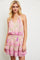 woman wearing a pink floral print tiered mini dress with spaghetti straps and a drawstring waist