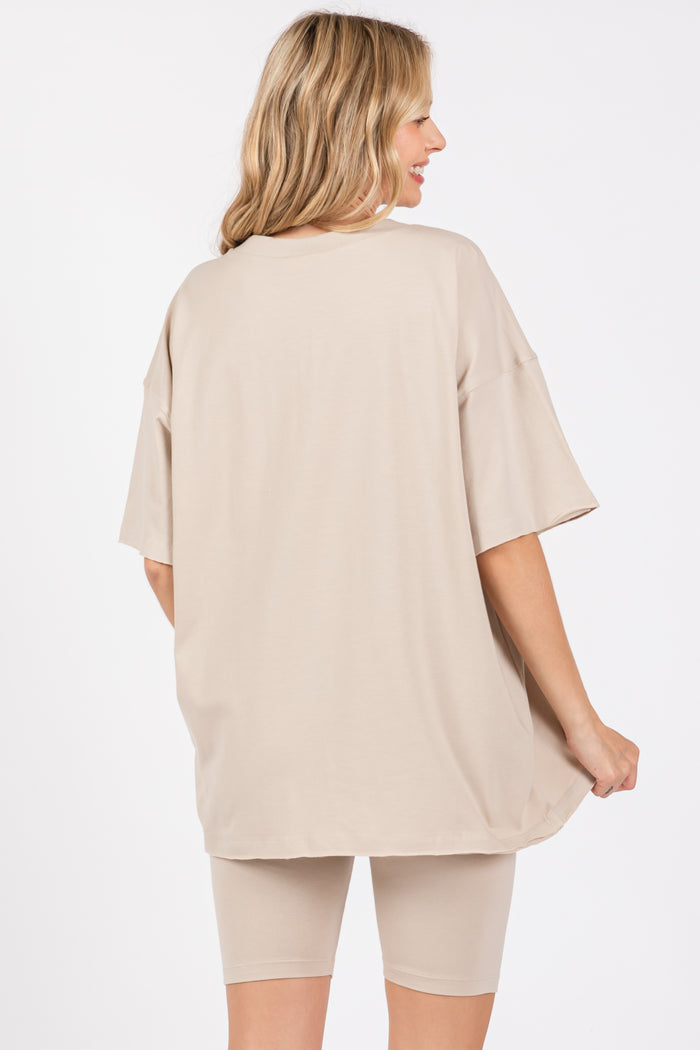woman wearing a beige oversized t-shirt with back view, styled with matching beige biker shorts