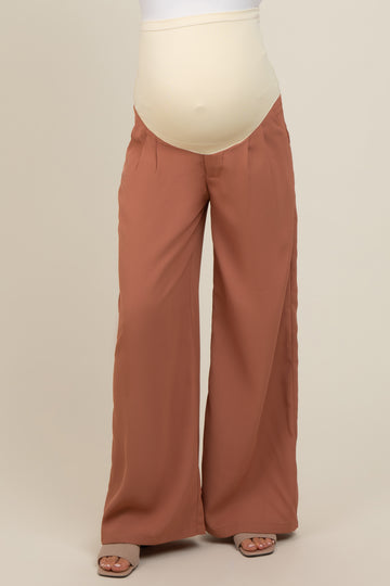 woman wearing rust-colored wide-leg maternity pants with a beige over-the-bump panel