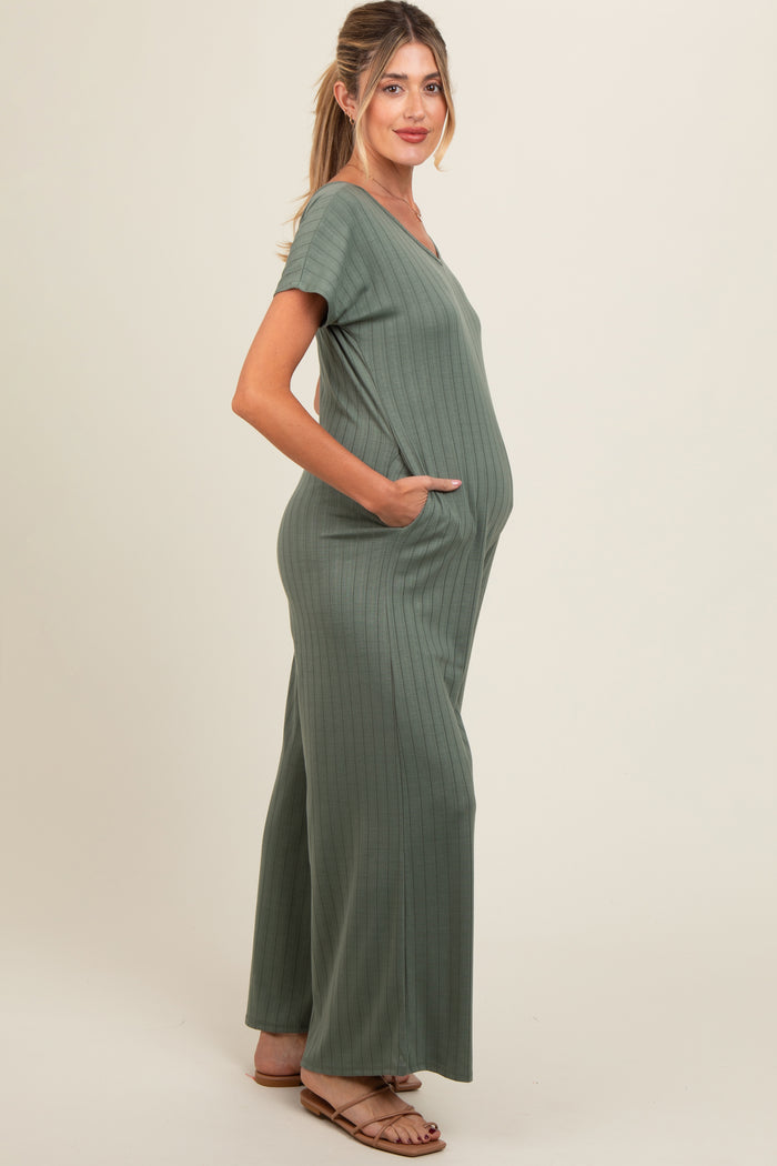 woman wearing a sage green ribbed maternity jumpsuit with pockets and a visible baby bump