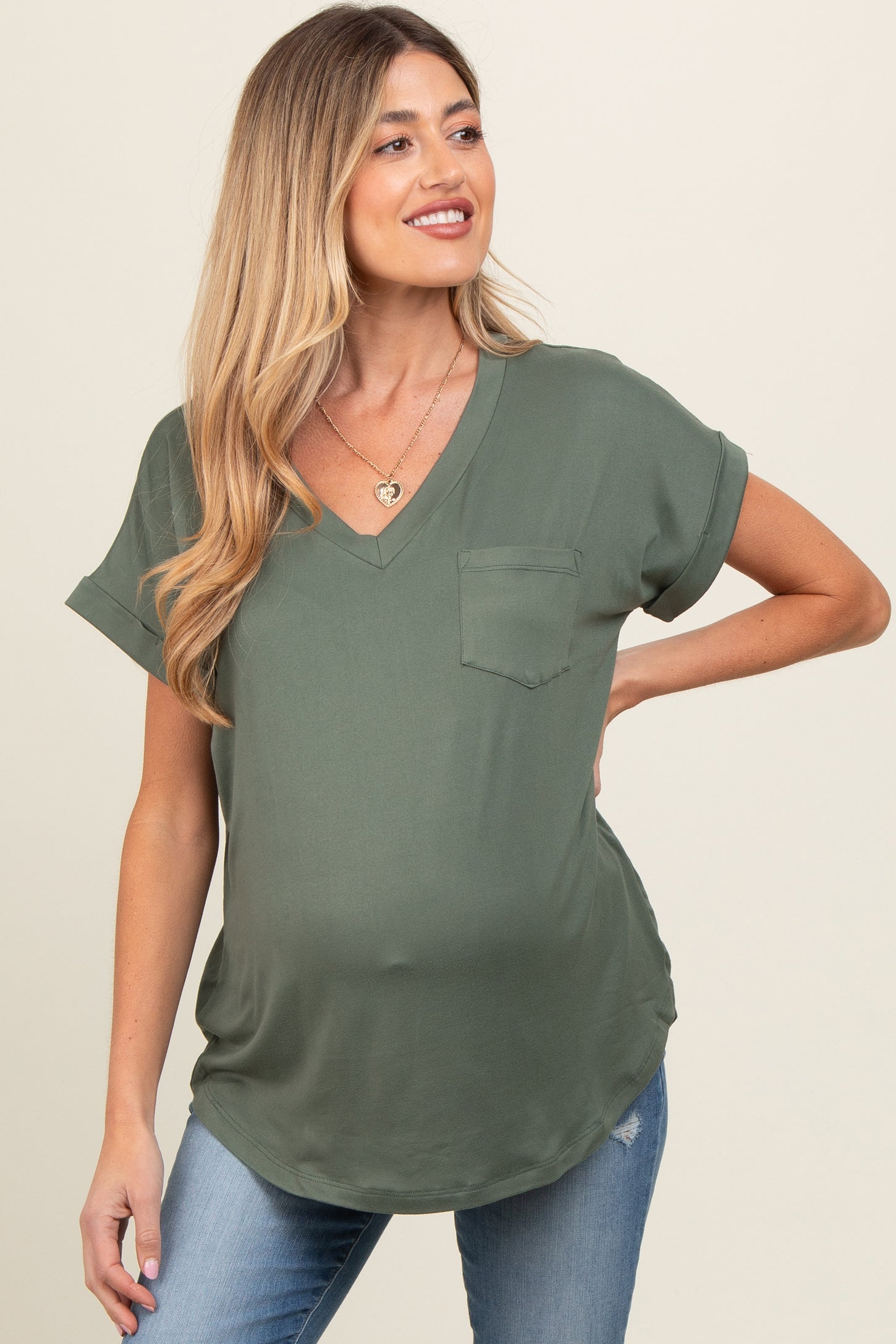 woman wearing an olive green short sleeve maternity top with a v-neck and pocket, showcasing her baby bump