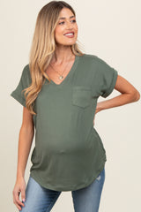 woman wearing an olive green short sleeve maternity top with a v-neck and pocket, showcasing her baby bump