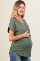 woman wearing a green v-neck maternity top with a pocket and a visible baby bump