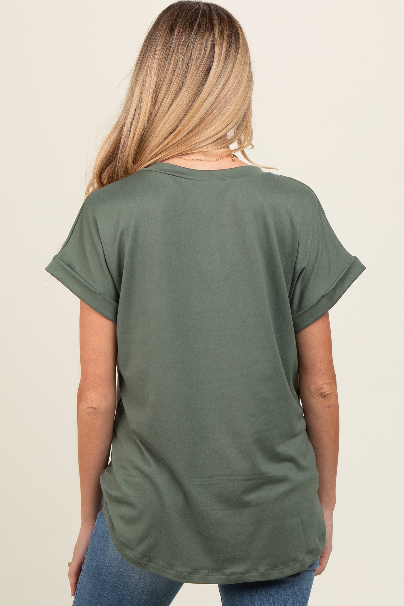 woman wearing a dark green short sleeve maternity top, showing a relaxed fit from the back