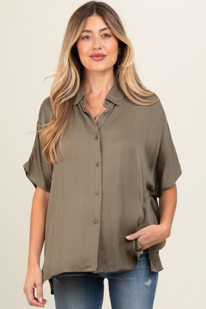 woman wearing an olive green short sleeve button-up maternity shirt, styled with loose fit and side pockets