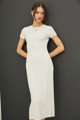 woman wearing a white short sleeve ribbed midi dress, standing against a black background