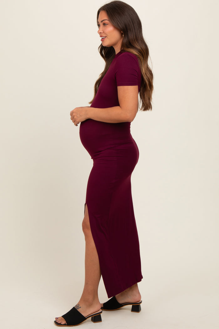 woman wearing a burgundy maternity maxi dress with short sleeves and a side slit, showing off her baby bump