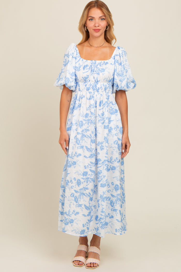 woman wearing a light blue floral maxi dress with puff sleeves and a square neckline