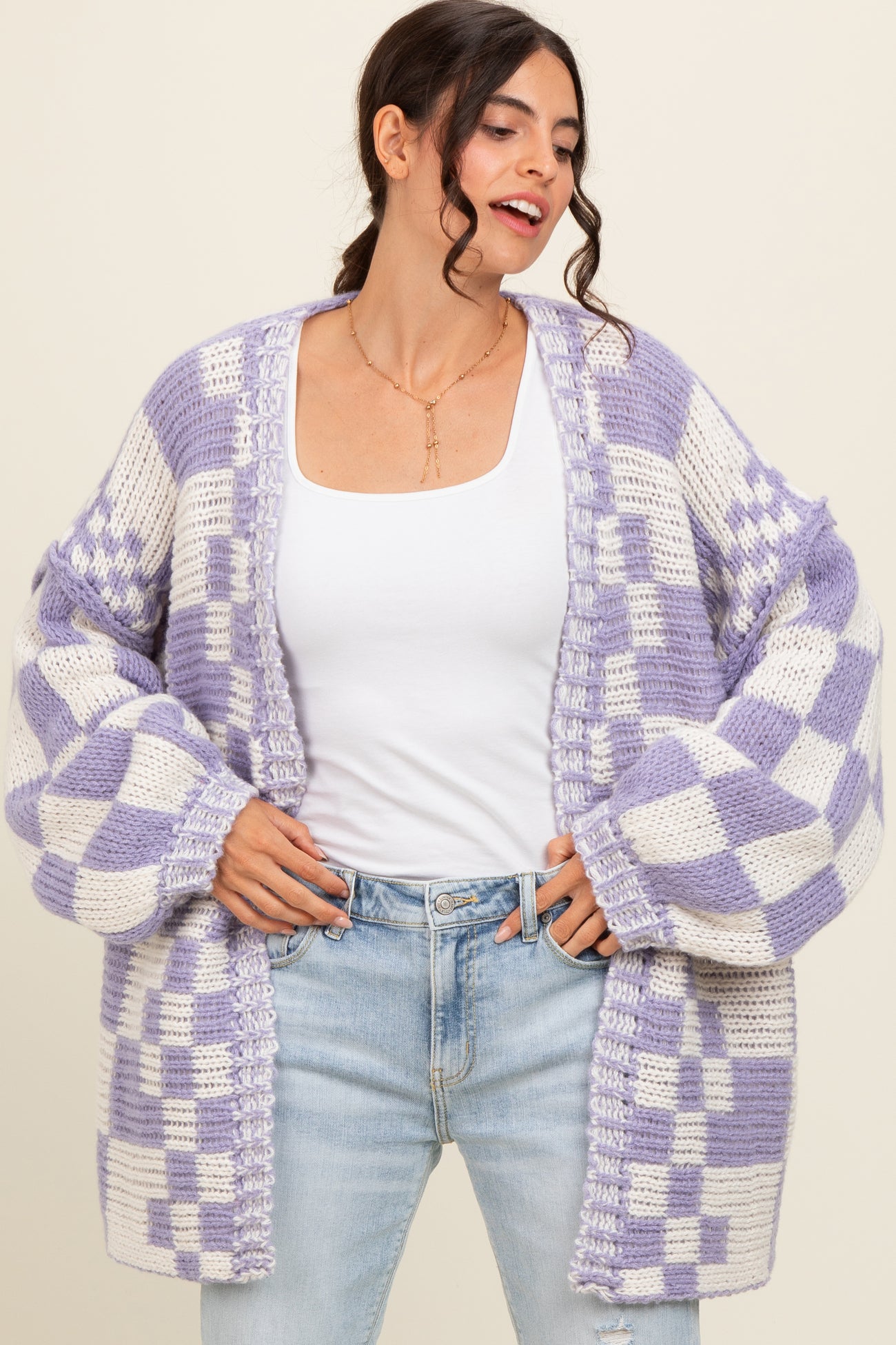 woman wearing a purple and white checkered oversized cardigan with bell sleeves and a white tank top underneath