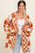 woman wearing an oversized orange and white checkered open knit cardigan over a white top and light blue jeans
