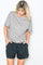 woman wearing a grey short sleeve t-shirt with a relaxed fit and black drawstring shorts, hands in pockets