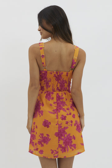 woman wearing a vibrant yellow floral sundress with pink patterns and a smocked back detail