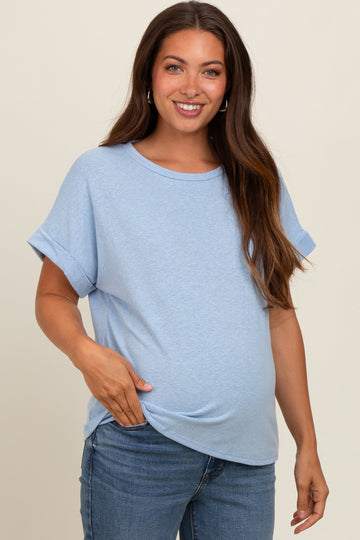 woman wearing a light blue short sleeve maternity top and holding her baby bump