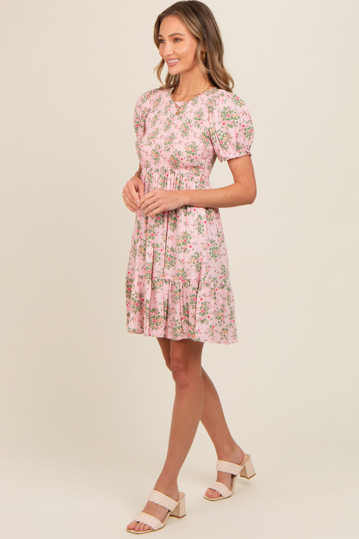 woman wearing a pink floral puff sleeve dress with a tiered hem and a relaxed fit