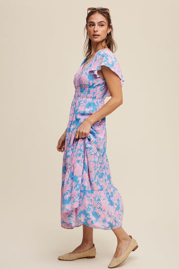 woman wearing a pink and blue floral maxi dress with short flutter sleeves and a smocked bodice