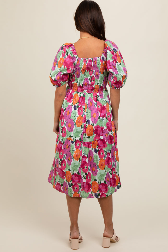 woman wearing a colorful floral maternity dress with puff sleeves and a smocked bodice, seen from the back