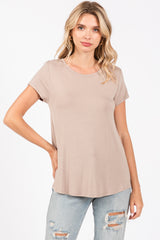 woman wearing a light taupe short sleeve top paired with distressed light blue jeans