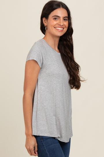 woman wearing a gray short sleeve t-shirt and blue jeans, smiling at the camera