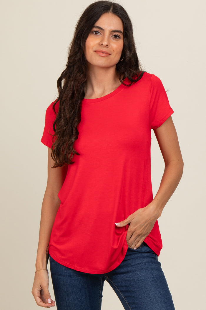 woman wearing a bright red short sleeve top with a relaxed fit and rounded hem, paired with blue jeans