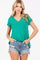 woman wearing a green v-neck t-shirt and distressed denim shorts with hands in pockets