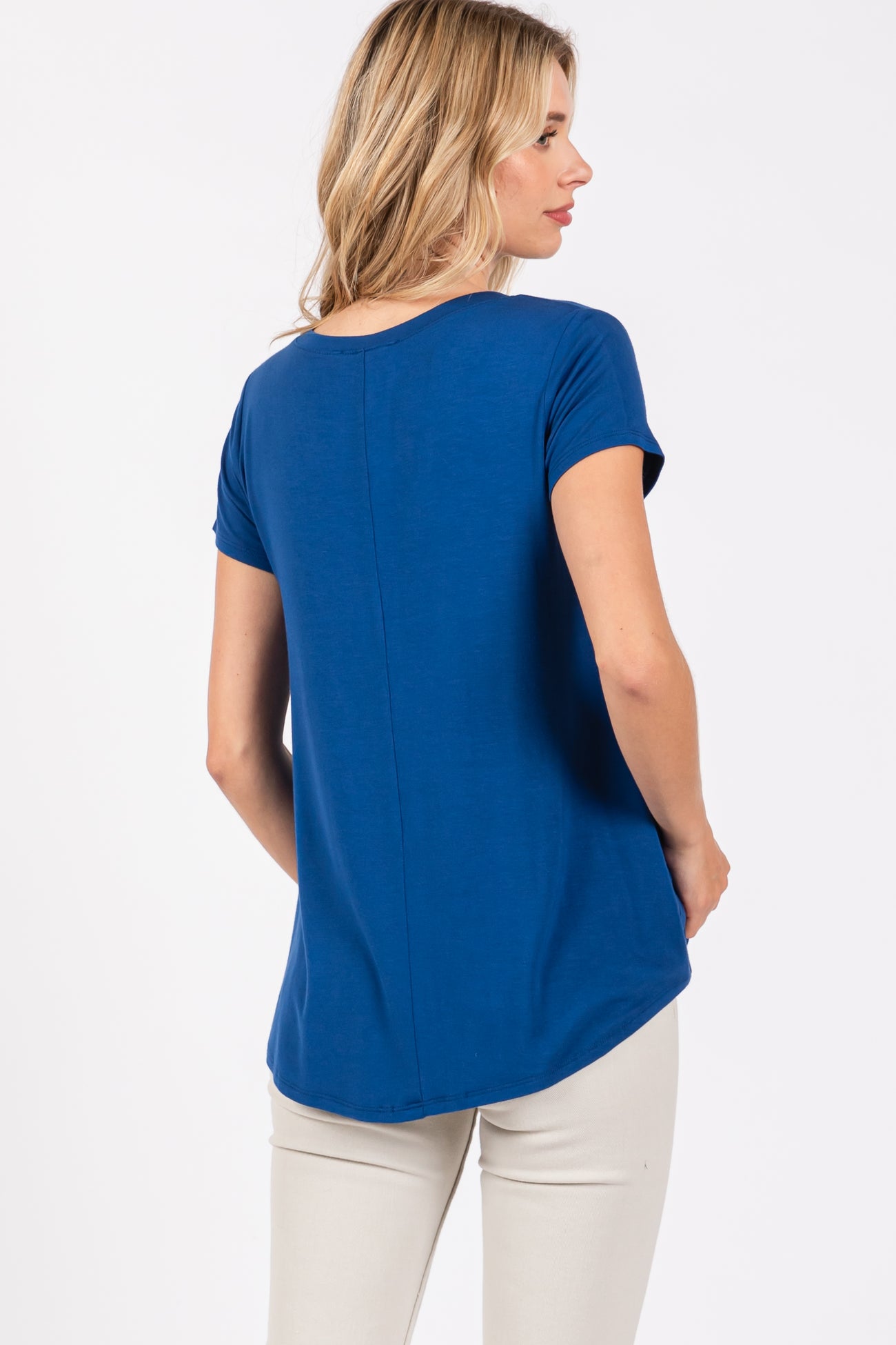 woman wearing a blue short sleeve top viewed from the back, paired with light beige pants