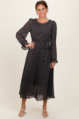 woman wearing a dark floral midi dress with long sleeves and ruffled cuffs, smiling at the camera