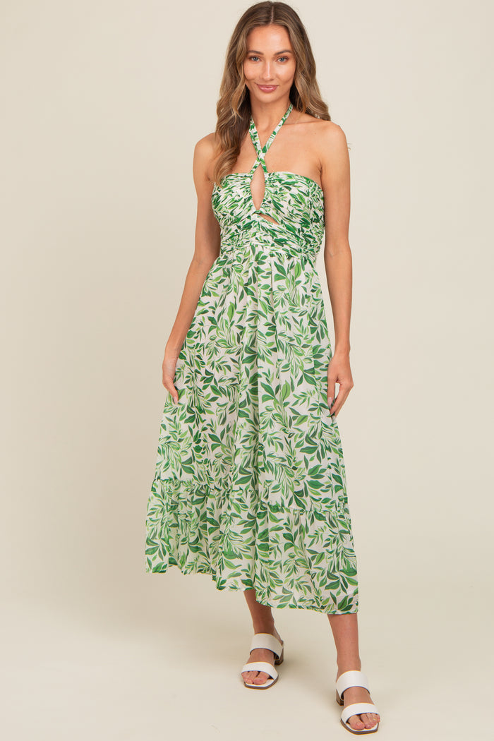 woman wearing a green leaf print halter neck midi dress with a keyhole detail and a flowy skirt