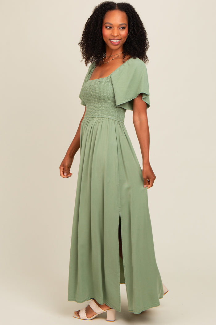 woman wearing a light green maxi dress with a smocked bodice and short sleeves, featuring a side slit