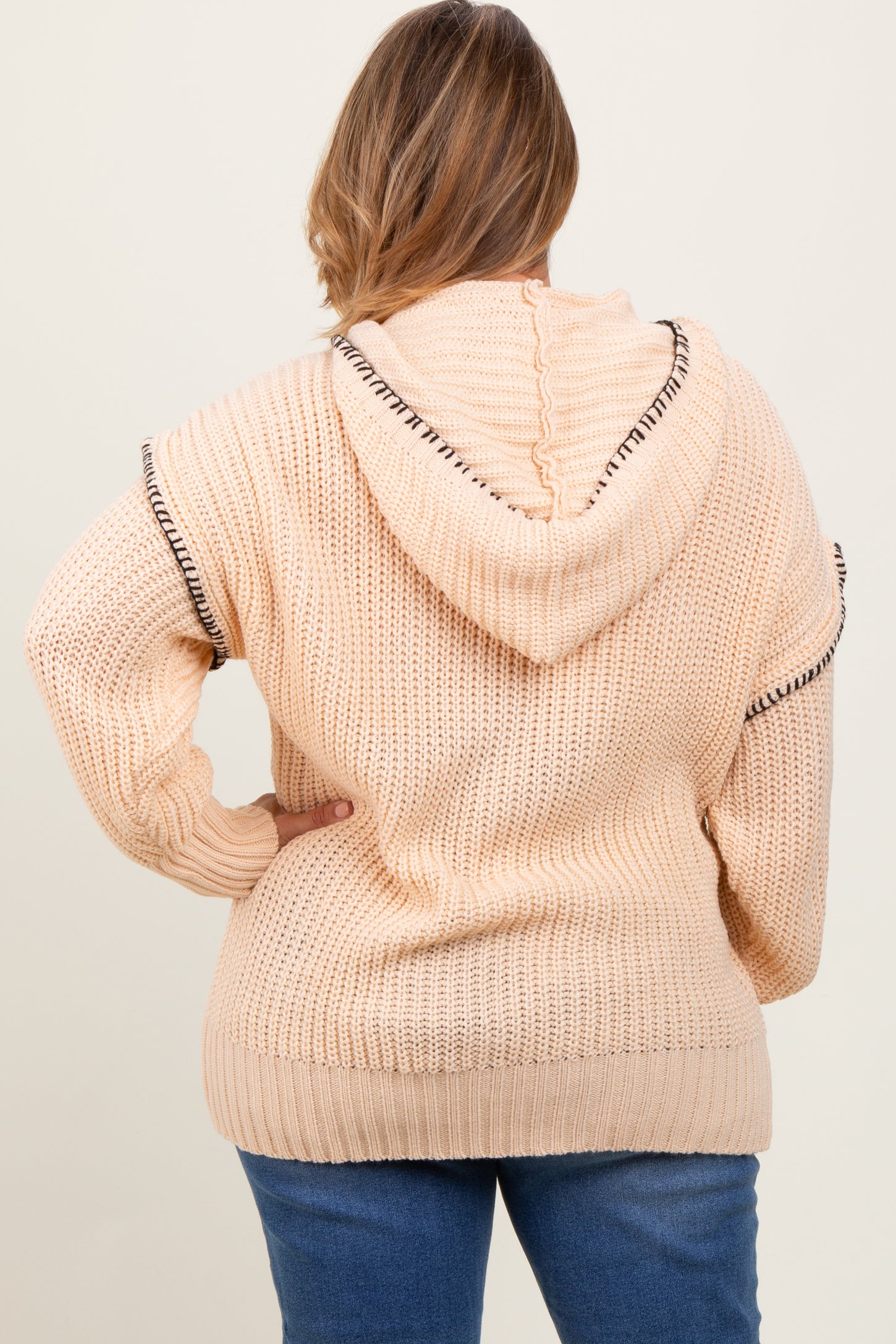 woman wearing a light peach knit maternity plus hoodie with a hood and contrasting trim, seen from the back