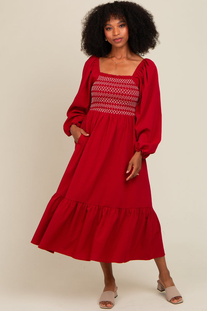 woman wearing a red smocked maxi dress with puff sleeves and a flounced hemline