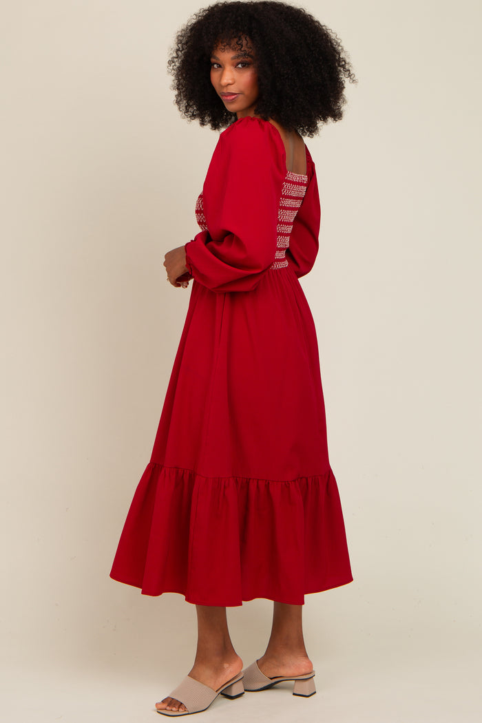 woman wearing a red long sleeve dress with ruffle hem and back detailing, standing sideways against a light background