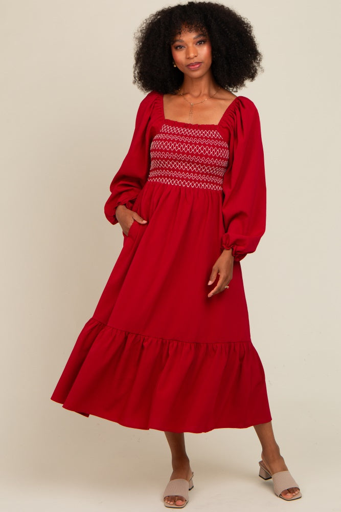 woman wearing a red smocked maxi dress with puff sleeves and a flounced hemline