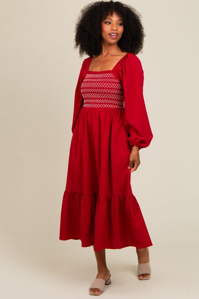 woman wearing a red puff sleeve midi dress with smocked bodice and ruffled hem, standing on a neutral background