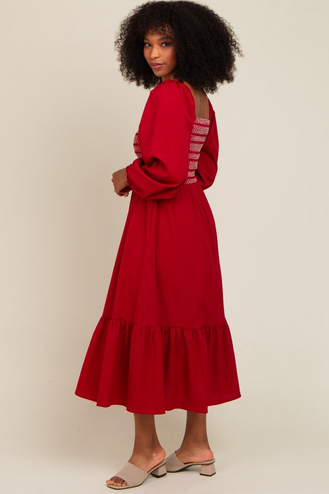 woman wearing a red long sleeve dress with ruffle hem and back detailing, standing sideways against a light background