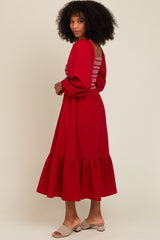woman wearing a red long sleeve dress with ruffle hem and back detailing, standing sideways against a light background