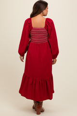 woman wearing a red maternity dress with smocked back and balloon sleeves, featuring a ruffled hem