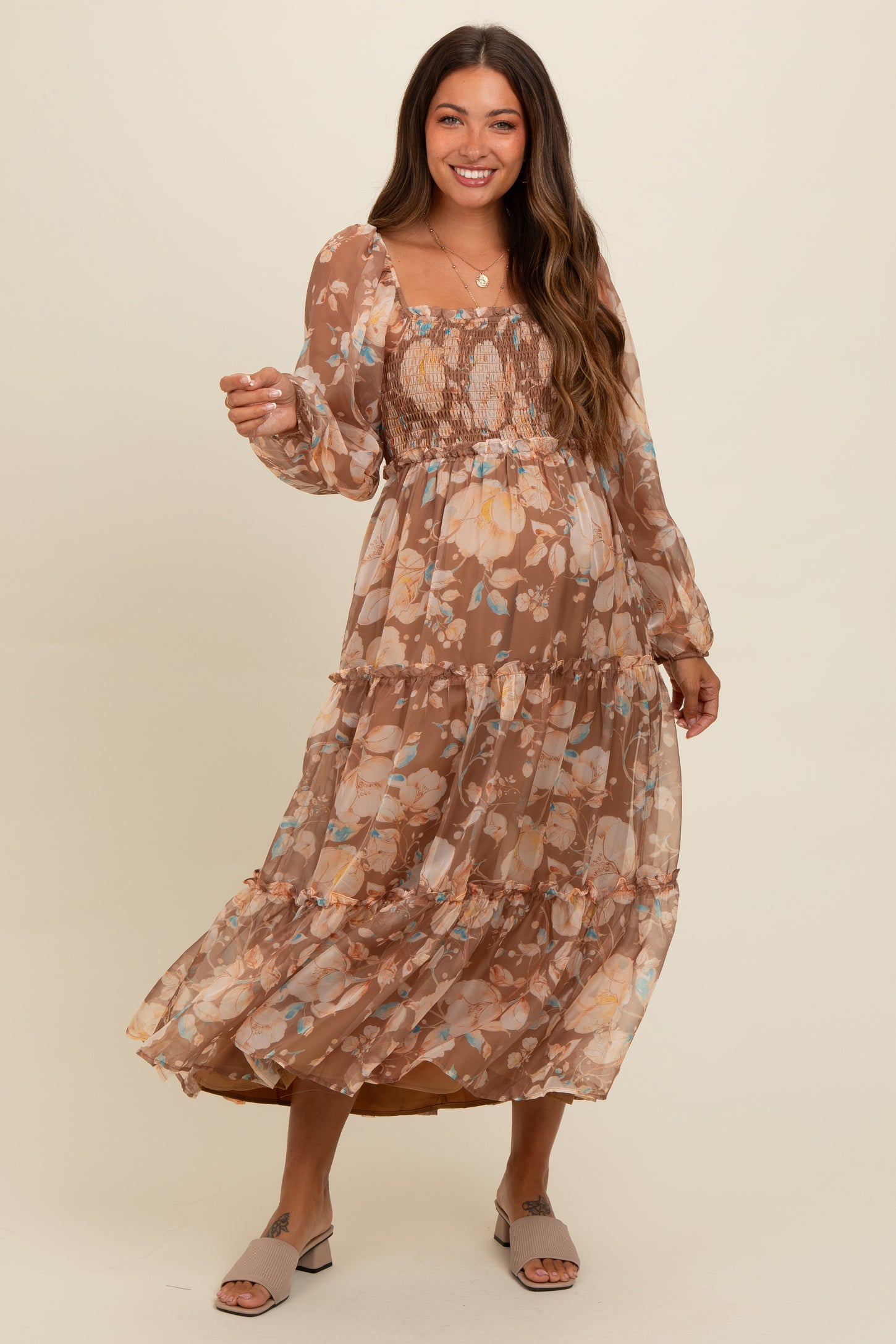 woman wearing a brown floral maternity maxi dress with long sleeves and a smocked bodice