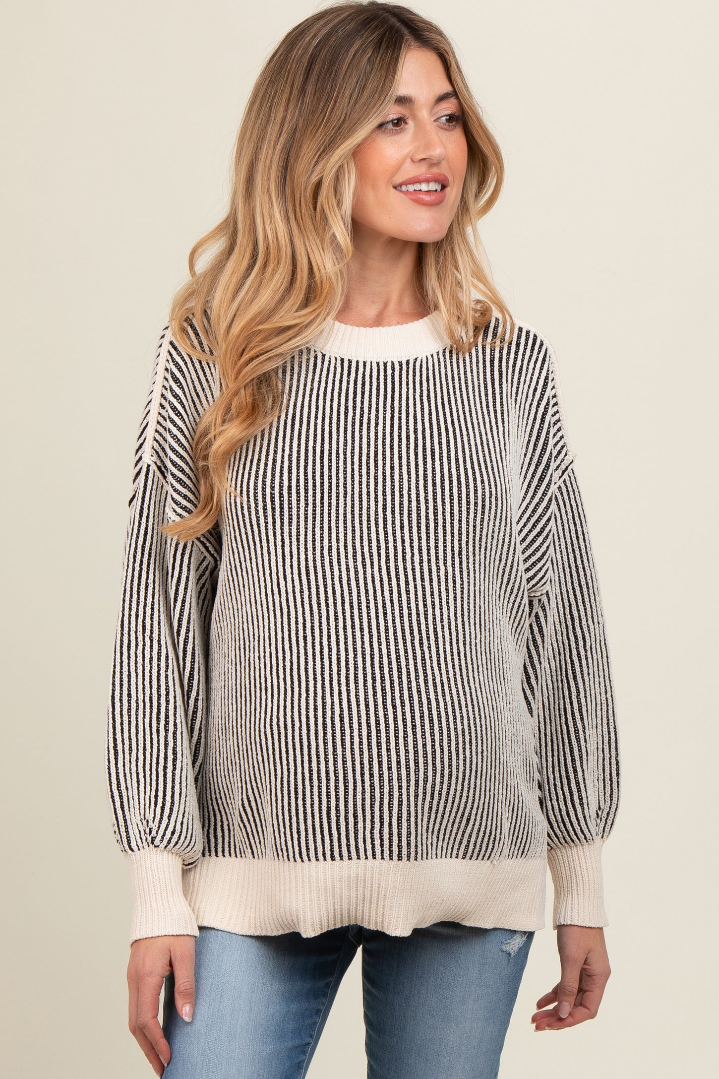 woman wearing a striped cream and black maternity sweater with balloon sleeves and a relaxed fit