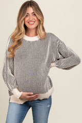 woman wearing a black and white striped maternity sweater and holding her baby bump while smiling