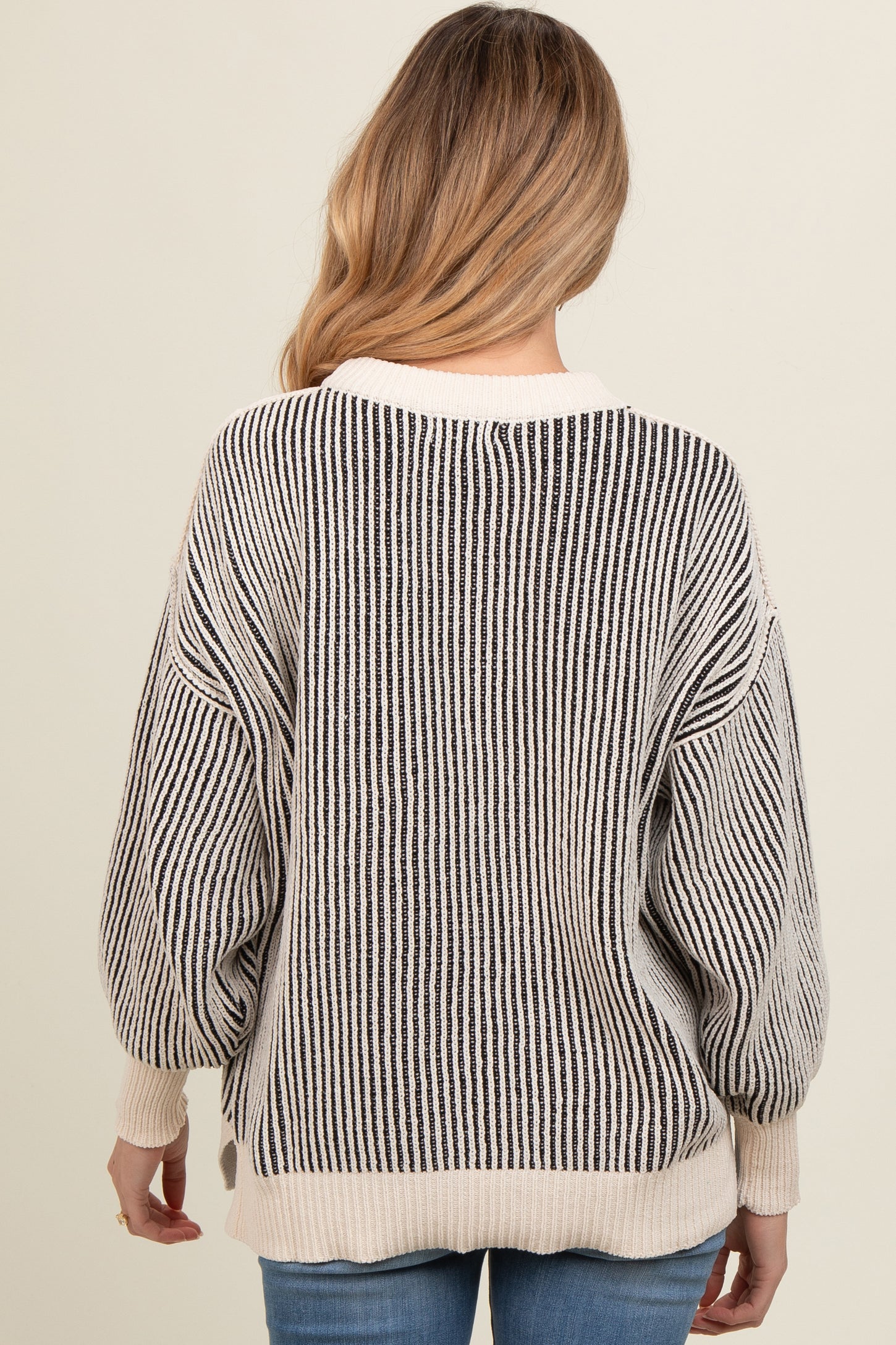 woman wearing a maternity oversized striped sweater, featuring a round neckline and balloon sleeves, viewed from the back